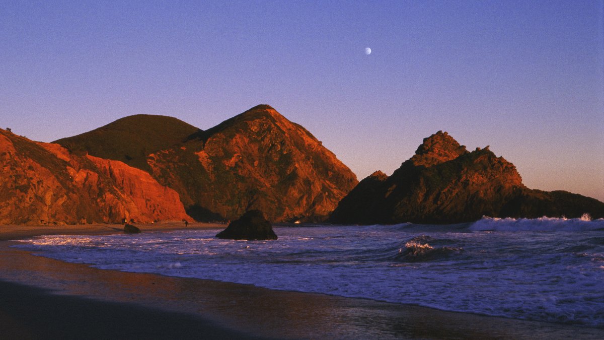 Moonrise over a Pacific cove at dusk